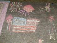 sidewalk chalk artwork red white and blue US flag, red white and blue firework rockets exploding