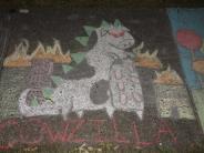 sidewalk chalk art of a black and white cow with green scales on it's back to appear like a dragon cow and flames in the back