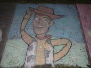 sidewalk chalk art drawing of woody character in cowboy vest cowboy hat and smiling