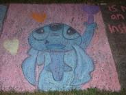 sidewalk chalk drawing of blue character with big black eyes holding a purple scepter and looking to the pink sky