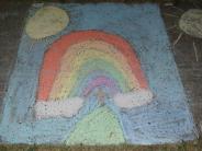 sidewalk chalk art rainbow coming from white clouds and a blue sky yellow sun