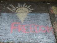 sidewalk chalk art yellow sunshine above blue water with text FREEDOM