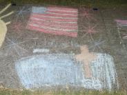 child's sidewalk chalk artwork of cross American Flag yellow sunshine and stars